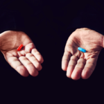 Holding a red and blue pill in each hand