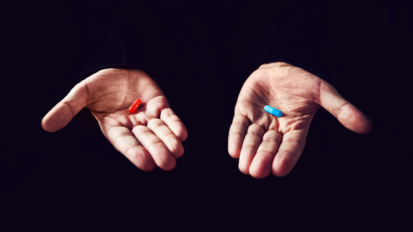 Holding a red and blue pill in each hand